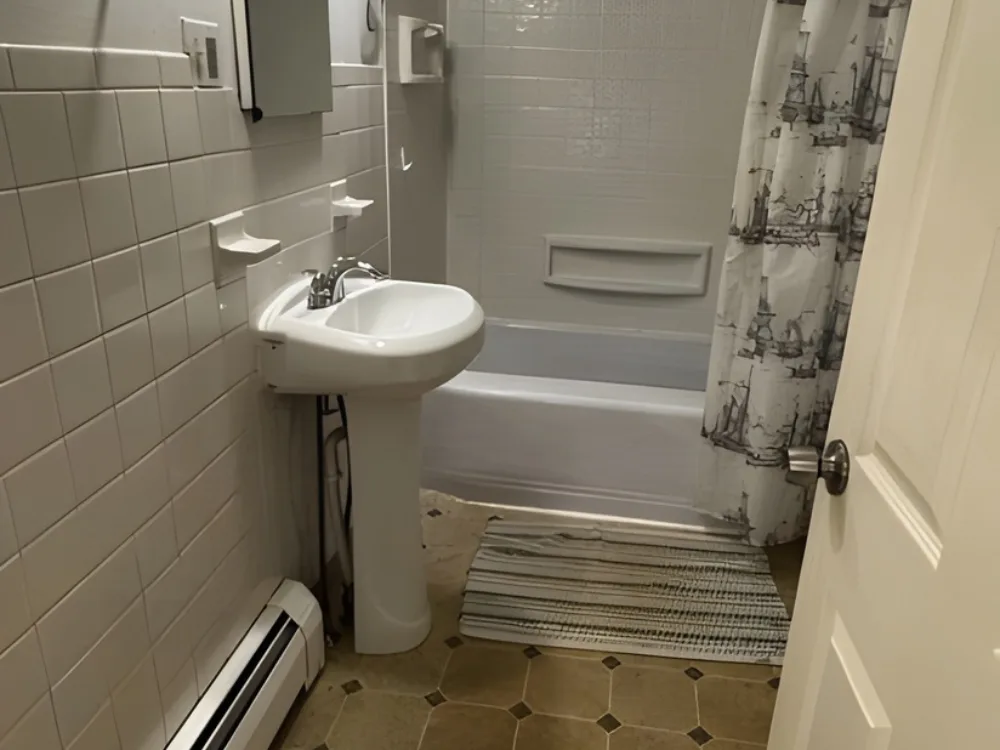 Bathroom renovation update showing pedestal sink, wall tile, and bathtub