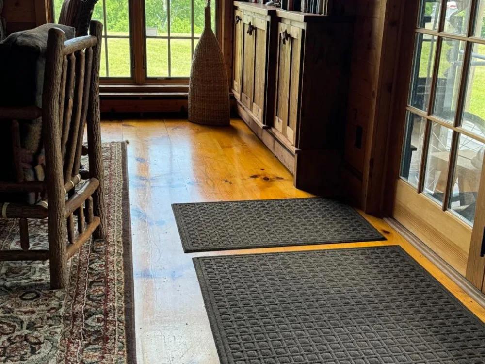 Close-up view of textured entry mats on a polished wooden floor, showcasing the detailed results of a complete room cleaning.