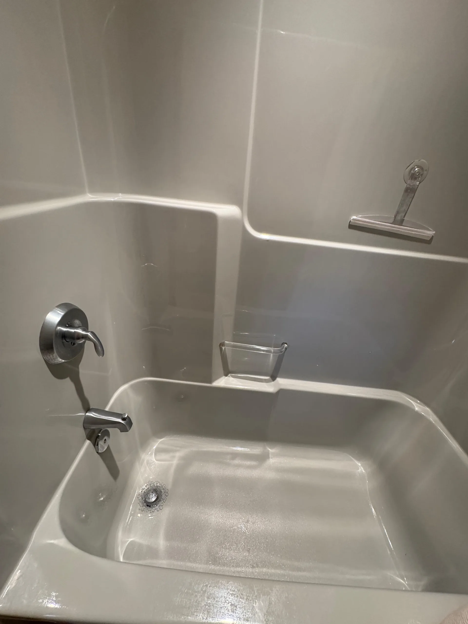The completed bathtub cleaning process showing a spotless white fiberglass shower and tub with shining chrome fixtures.